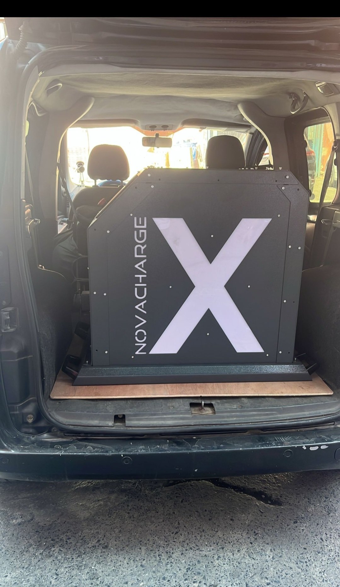 NovaCharge X electric vehicle charging station installed in car trunk with large X logo displayed