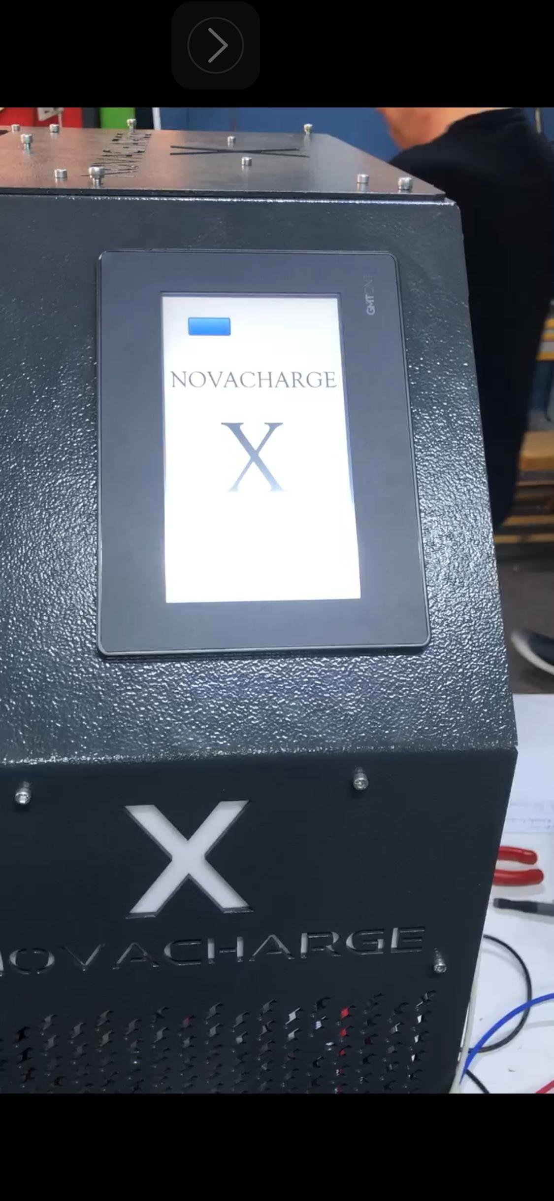NovaCharge X device with display screen and white X logo on black exterior box showing charging equipment