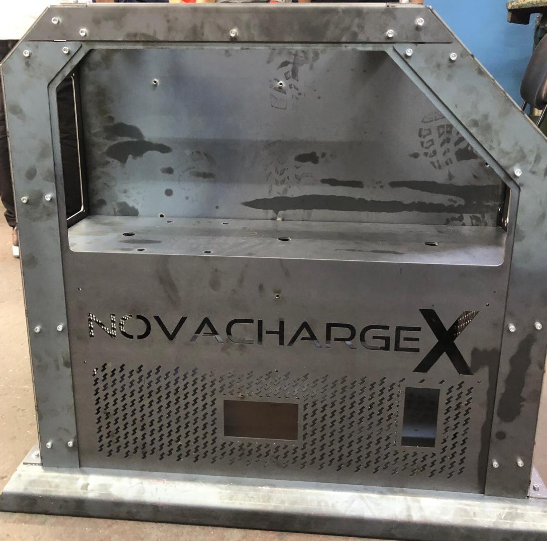 Industrial metal enclosure with SuperChargeX branding, featuring ventilation mesh and control panel on weathered exterior