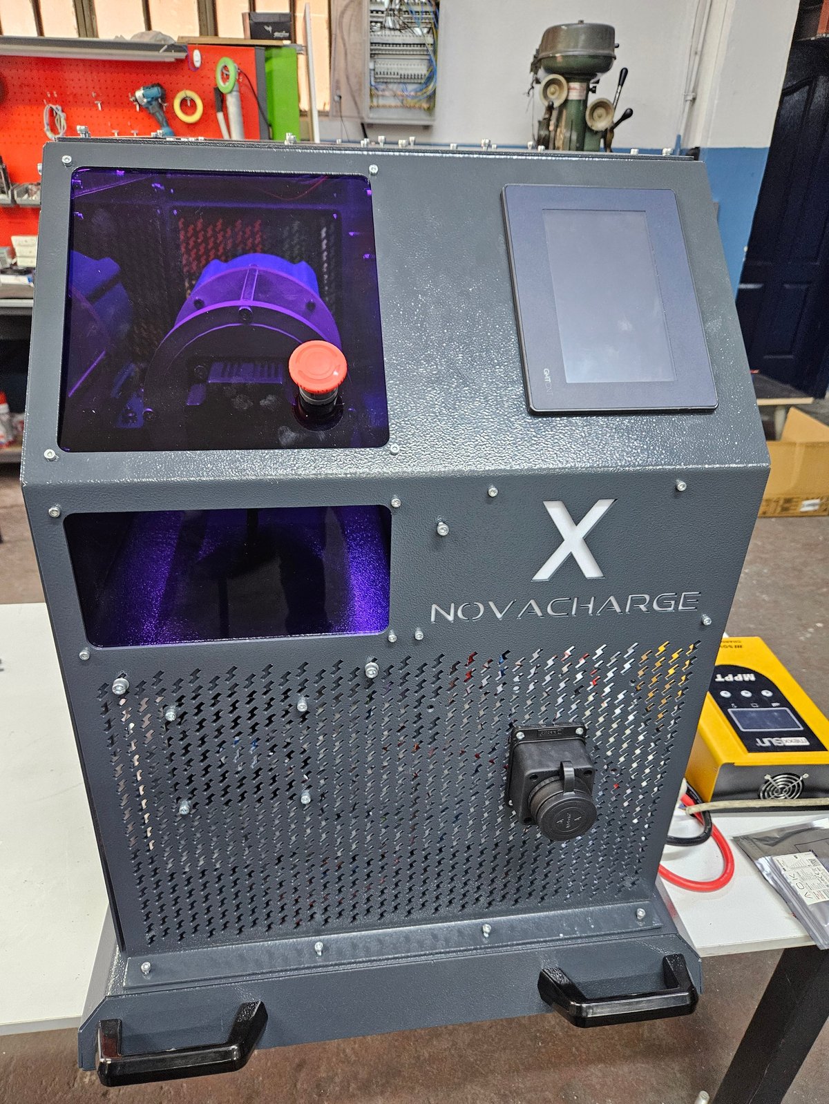 NovaCharge X desktop charging device with purple thermal display and orange control button in a workshop setting