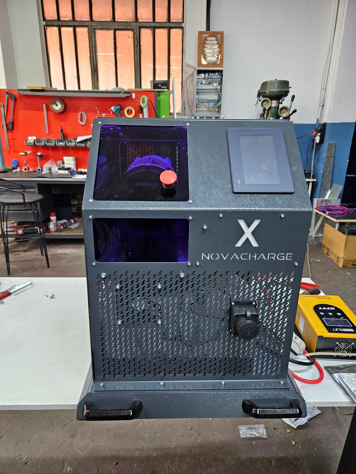 NovaCharge X 3D printer in workshop with red tool pegboard, control panel displays, and tools visible in background